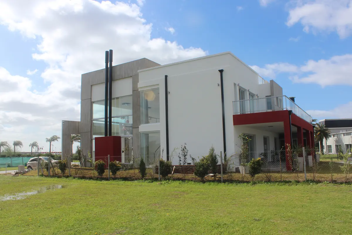 Fachada moderna de casa com grandes janelas e jardim — projeto Abierta al lago, por Marcela Romiti Arquitectura, em La Plata
