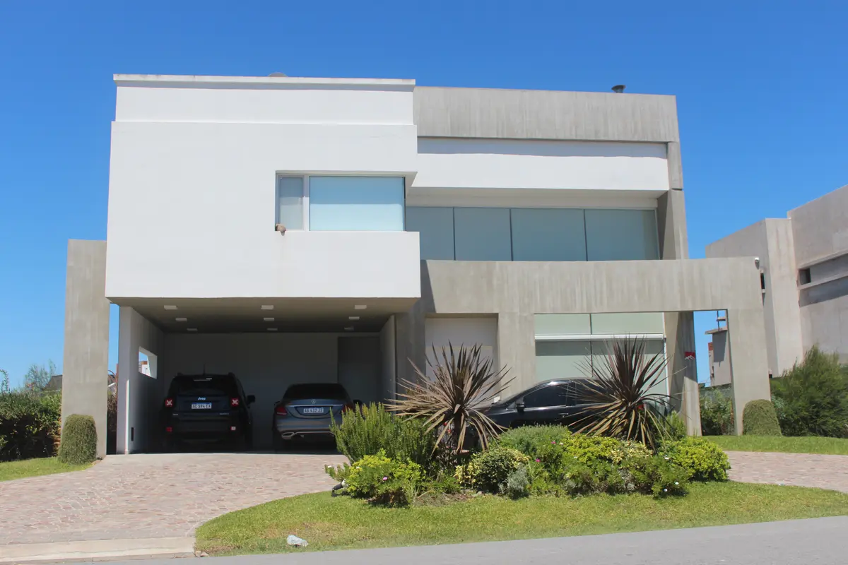 Fachada moderna de casa com concreto e janelas grandes — projeto Abierta al lago, por Marcela Romiti Arquitectura, em La Plata