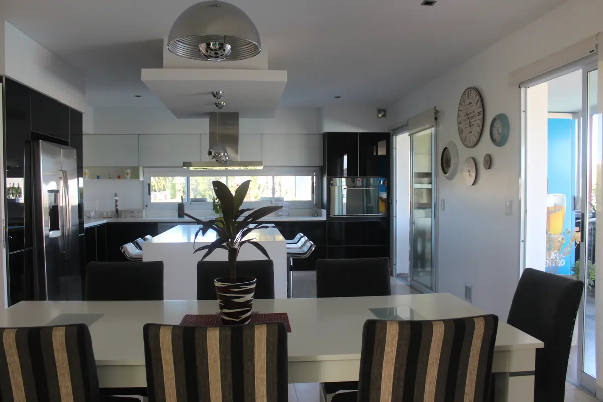 Cocina y comedor modernos de planta abierta con isla y sillas rayadas — proyecto Abierta al lago, por Marcela Romiti Arquitectura, en La Plata