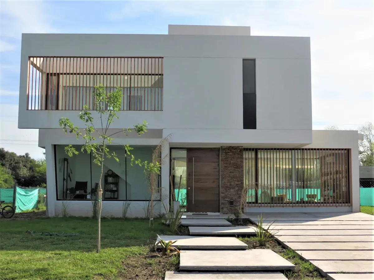 Fachada moderna com volumes geométricos e brise de madeira — projeto Casa MB- Harás Sta. María, por Olivieri Arquitectura, em Haras Santa María