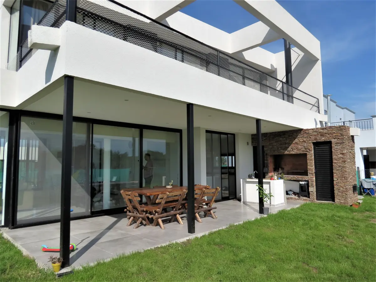 Fachada moderna com terraço, sala de jantar externa e deck — projeto Casa MB- Harás Sta. María, por Olivieri Arquitectura, em Haras Santa María