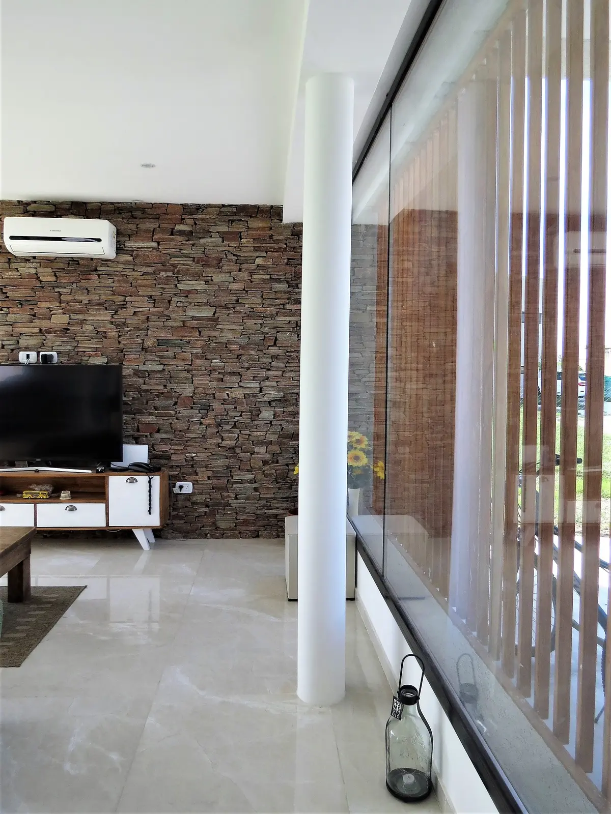 Living moderno con pared de piedra y pilar cilíndrico — proyecto Casa MB- Harás Sta. María , por Olivieri Arquitectura, en Haras Santa María