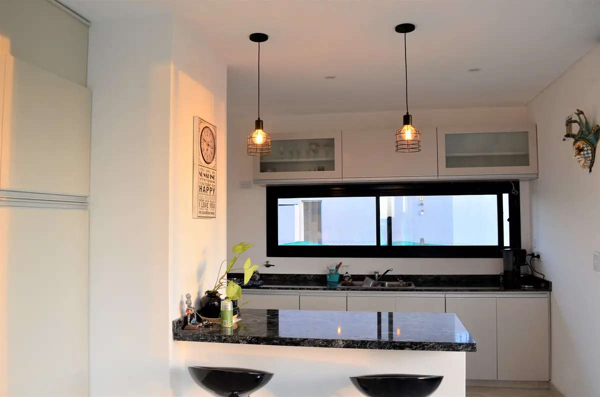 Cozinha moderna com ilha, bancada de mármore e detalhes industriais — projeto Casa MB- Harás Sta. María, por Olivieri Arquitectura, em Haras Santa María