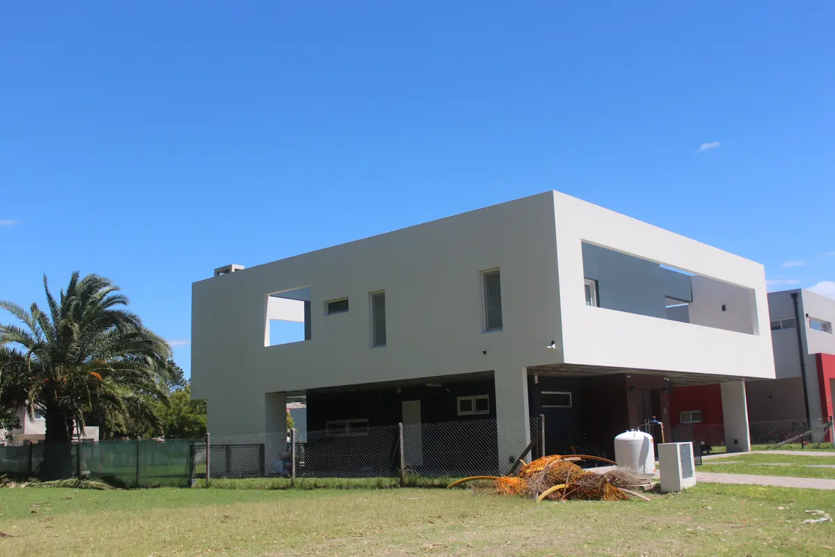Fachada moderna geométrica com amplas janelas e árvores frondosas — projeto Golondrinas 98, por Marcela Romiti Arquitectura, em La Plata