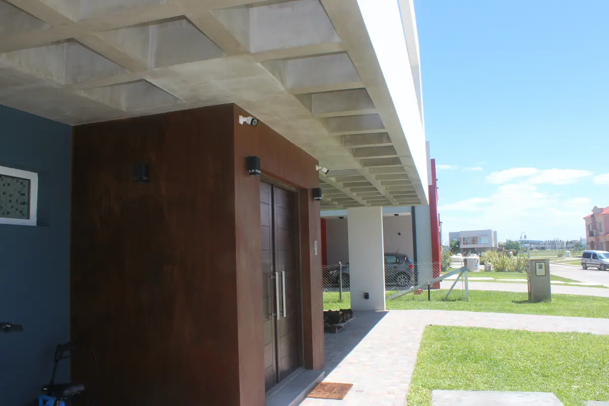 fachada moderna com teto de concreto em favo e portas de madeira — projeto Golondrinas 98, por Marcela Romiti Arquitectura, em La Plata