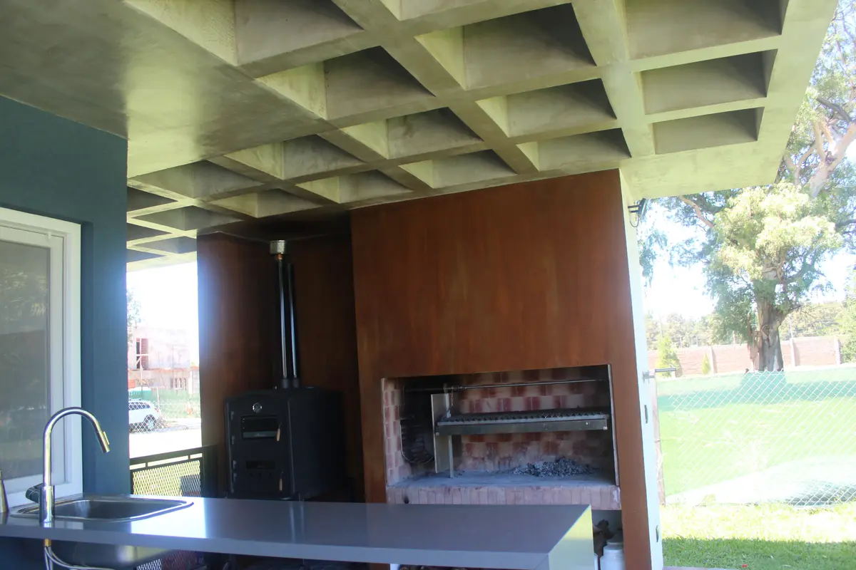 Àrea gourmet moderna com teto em concreto e churrasqueira embutida — projeto Golondrinas 98, por Marcela Romiti Arquitectura, em La Plata