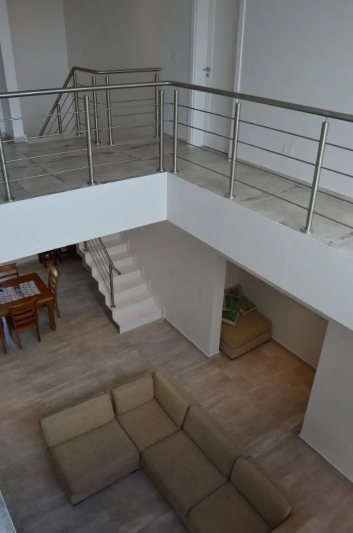 Interior moderno de dos plantas con escaleras flotantes y sofá seccional — proyecto Golondrinas 99, por Marcela Romiti Arquitectura, en La Plata