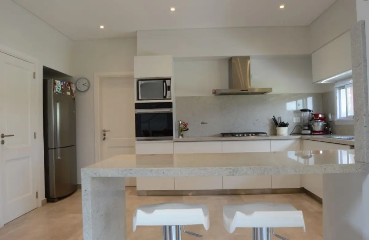 Cocina moderna, minimalista, con isla grande y electrodomésticos integrados — proyecto Golondrinas 99, por Marcela Romiti Arquitectura, en La Plata