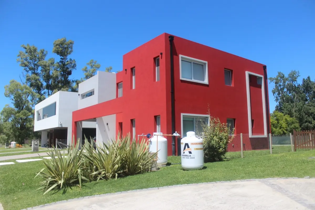 Casa moderna com fachada vermelha vibrante e jardim — projeto Golondrinas 99, por Marcela Romiti Arquitectura, em La Plata