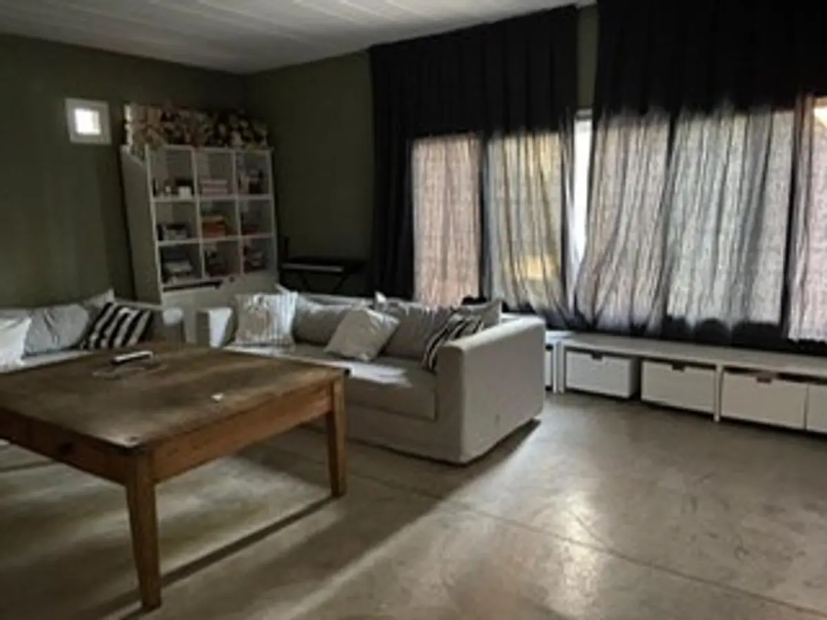 Living comedor moderno con sofá modular beige y mesa de centro rústica — proyecto Barrio Hindu, por Flor Martelli Diseñó y Arte, en Don Torcuato