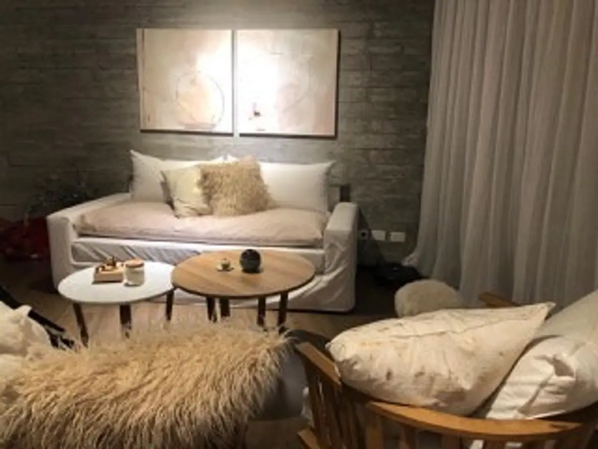 Sala moderna com parede de concreto, sofá bege e arte abstrata — projeto Omm!, por Flor Martelli Diseñó y Arte, em Punta Chica