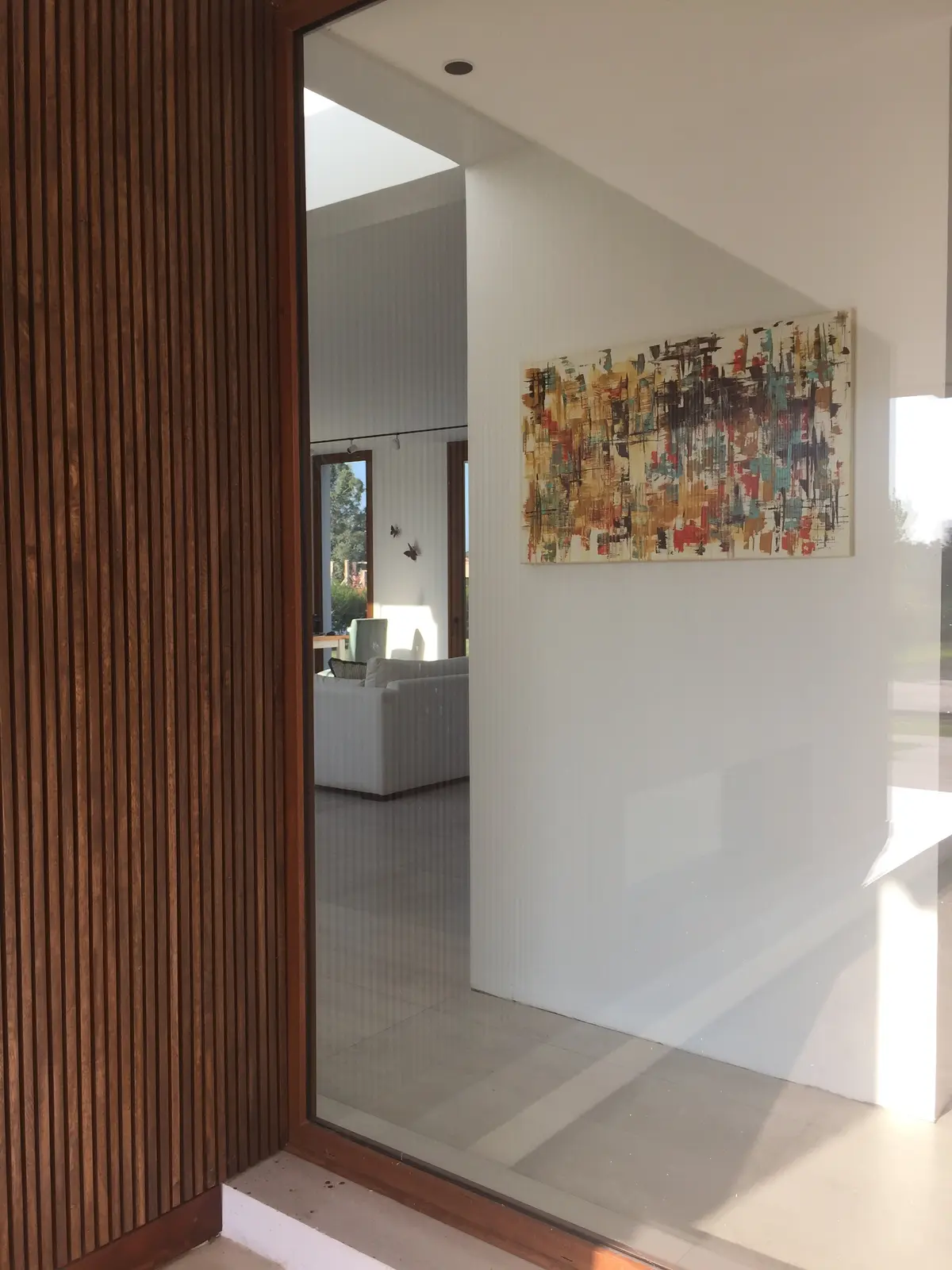 Hall de entrada moderno con pared de madera y arte abstracto — proyecto VM, por Estudio GR