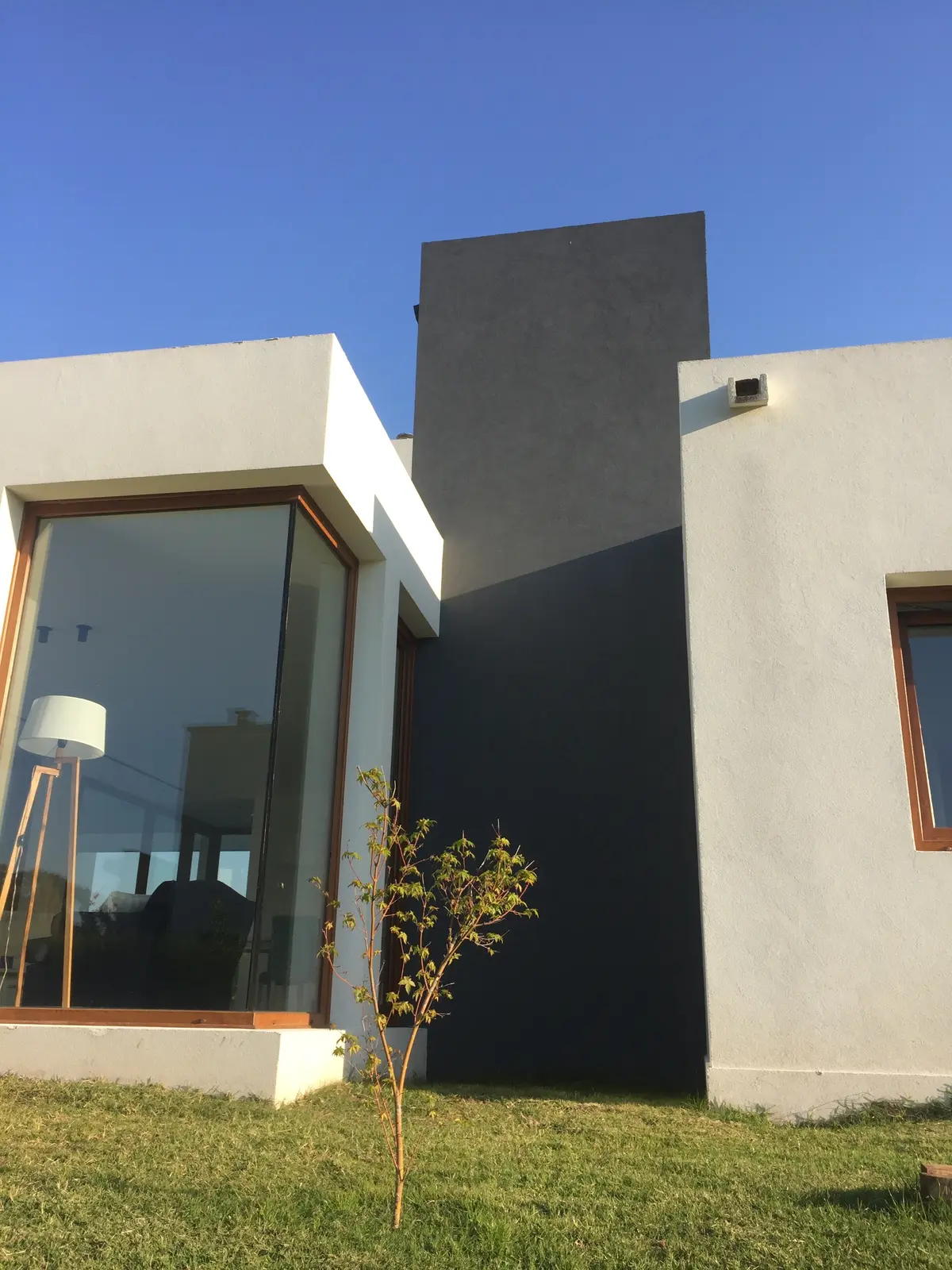 Fachada moderna de concreto com grandes janelas e jardim — projeto VM, por Estudio GR
