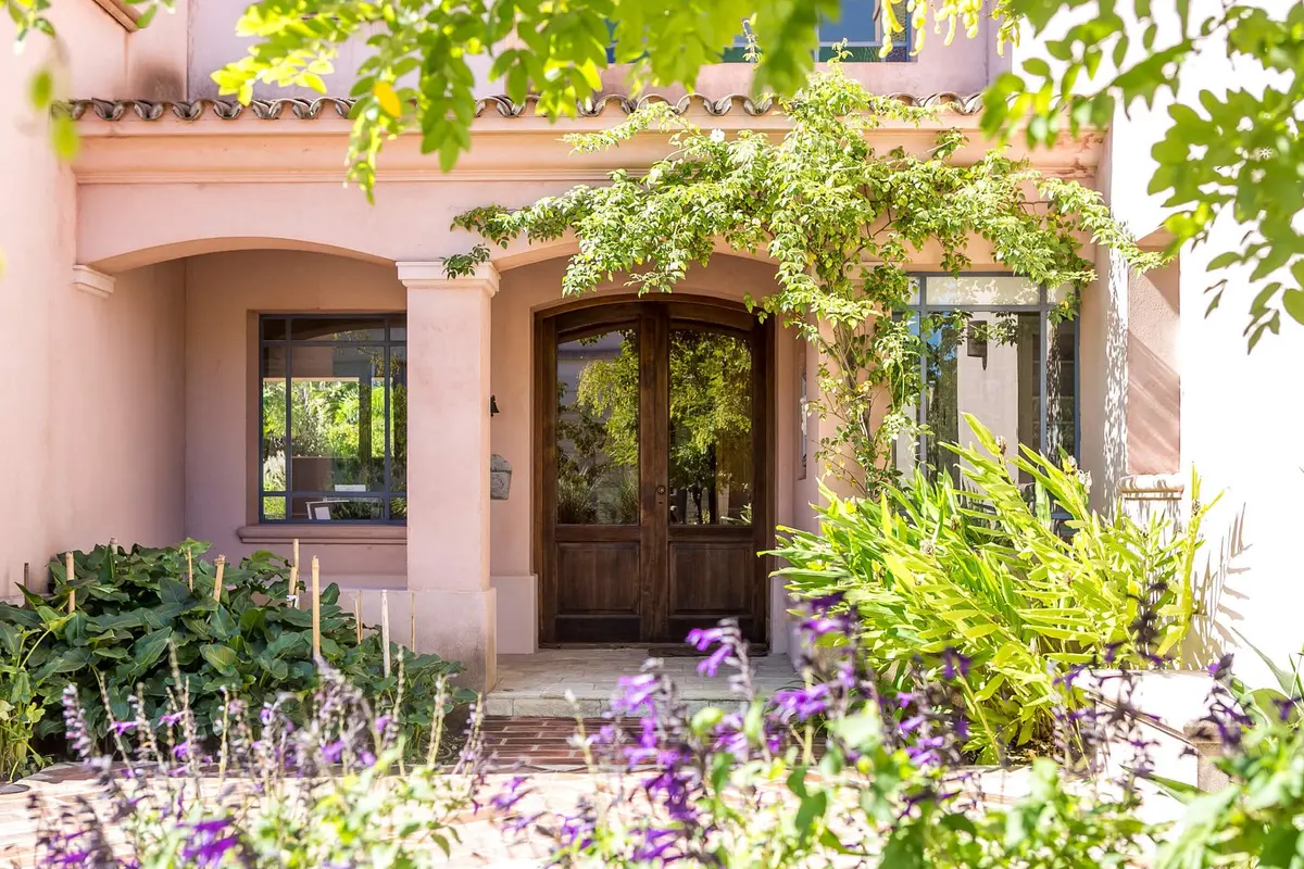 Fachada mediterránea con vegetación exuberante y detalles en piedra — proyecto Casa DG, por Ricardo Pereyra Iraola 