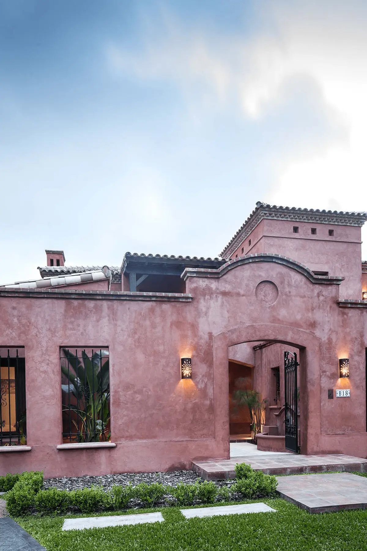 Fachada mediterrânea de casa com estuque rosa, arco e luzes ornamentais — projeto Rincones que Inspiran, por Ricardo Pereyra Iraola