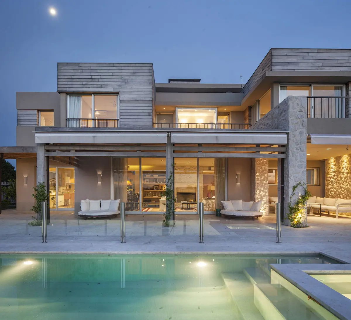 Fachada moderna con piscina y madera, vista nocturna — proyecto Casa RC, por Ricardo Pereyra Iraola 