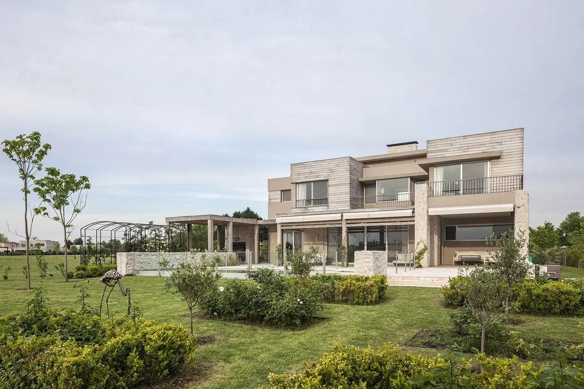 Fachada moderna com amplas janelas e jardim exuberante — projeto Casa RC, por Ricardo Pereyra Iraola
