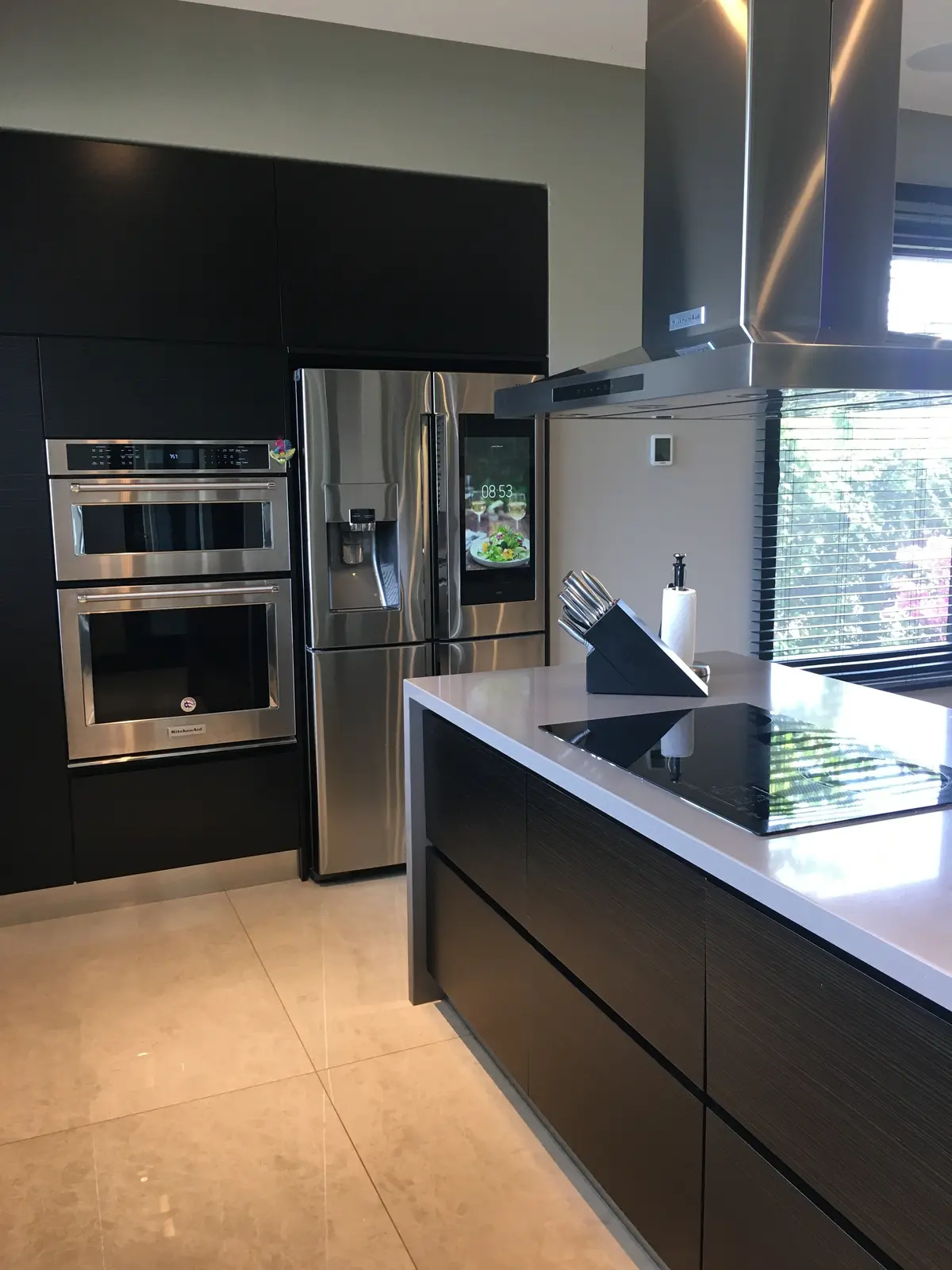 Cozinha moderna com ilha, eletrodomésticos integrados e armários escuros — projeto Casa Abril Club de Campo, por byb.arquitectas, em Abril Club De Campo