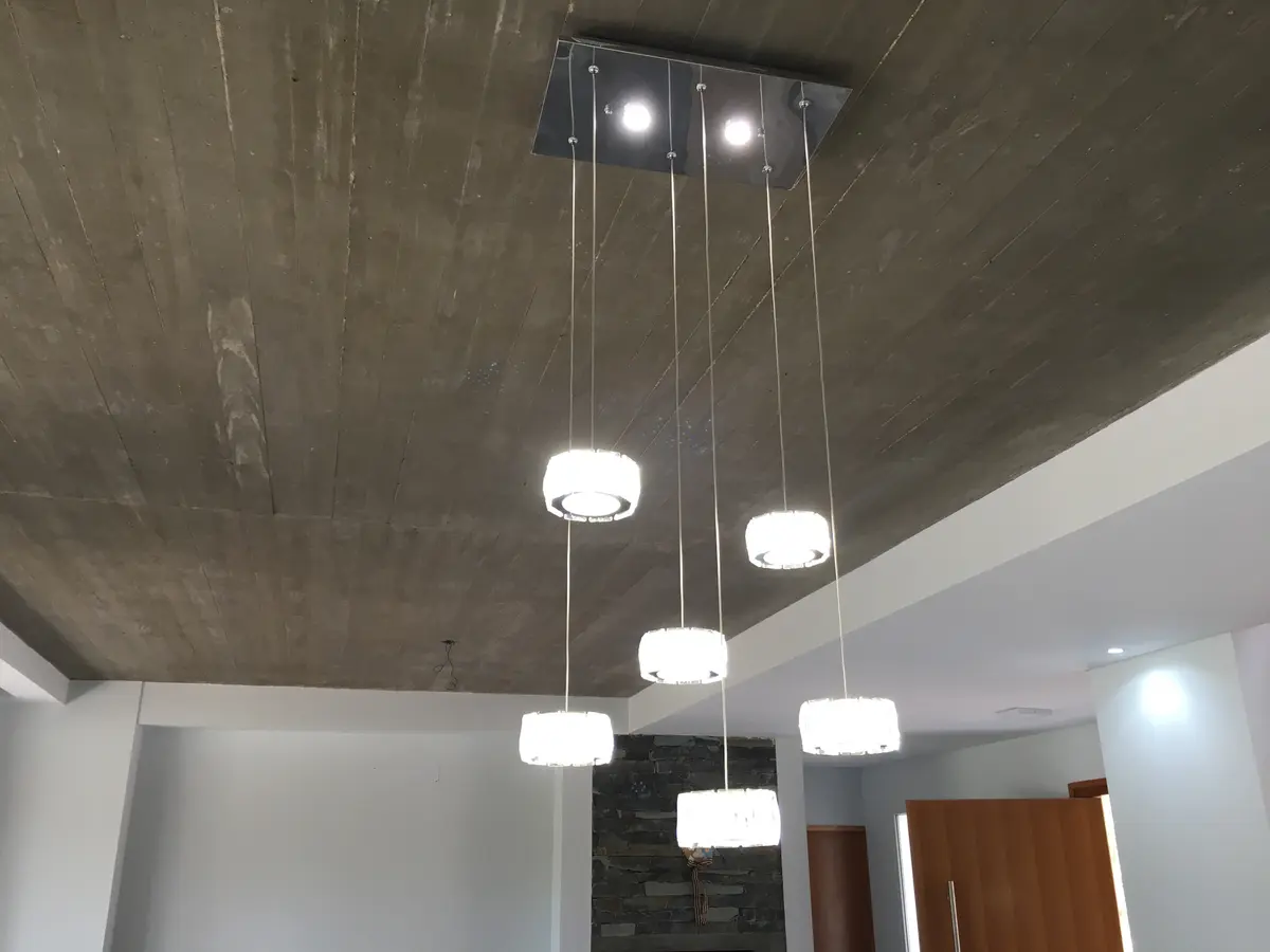 Sala de estar moderna con techo de hormigón visto y lámparas colgantes — proyecto Casa VR, por Sacco Maximiliano Arq., en Villa Robles