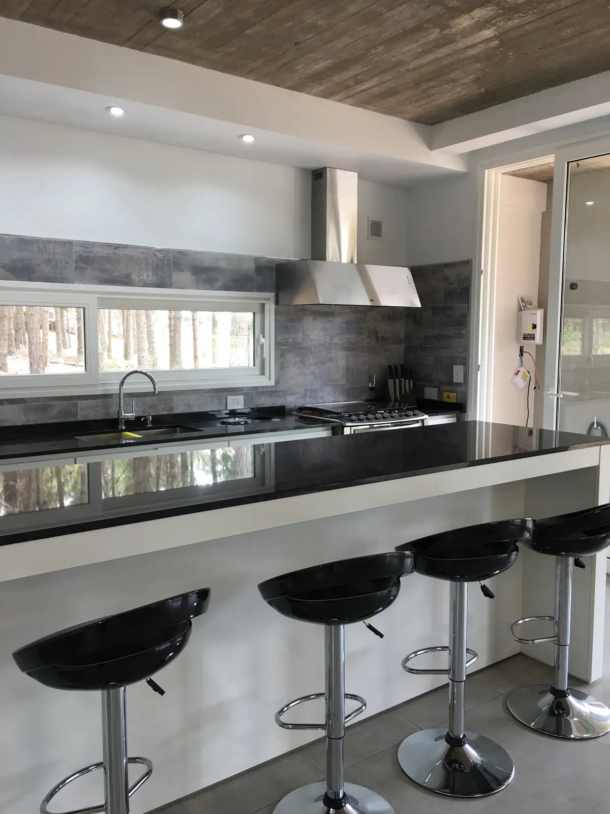 Cozinha moderna com ilha, teto de concreto e bancos — projeto Casa VR, por Sacco Maximiliano Arq., em Villa Robles