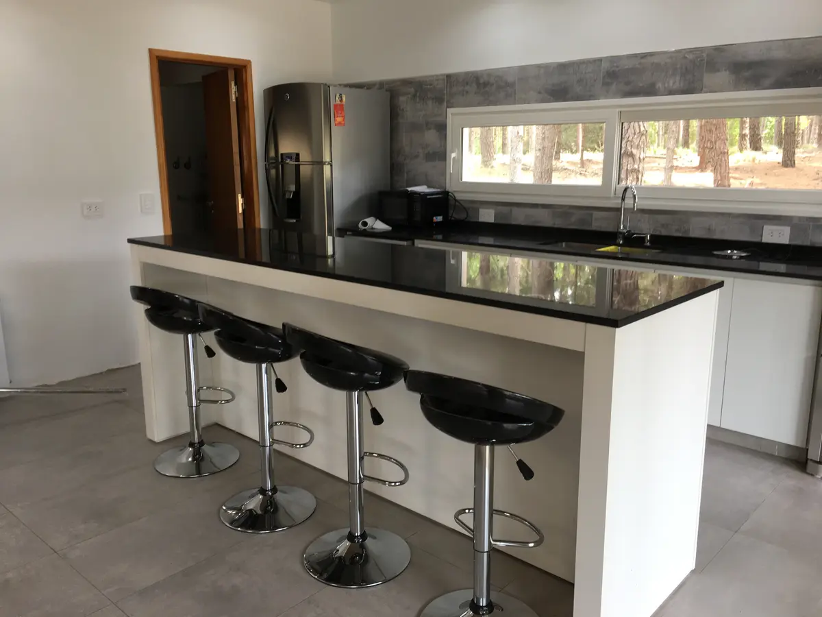 Cozinha moderna aberta com ilha grande, balcão e banquetas — projeto Casa VR, por Sacco Maximiliano Arq., em Villa Robles