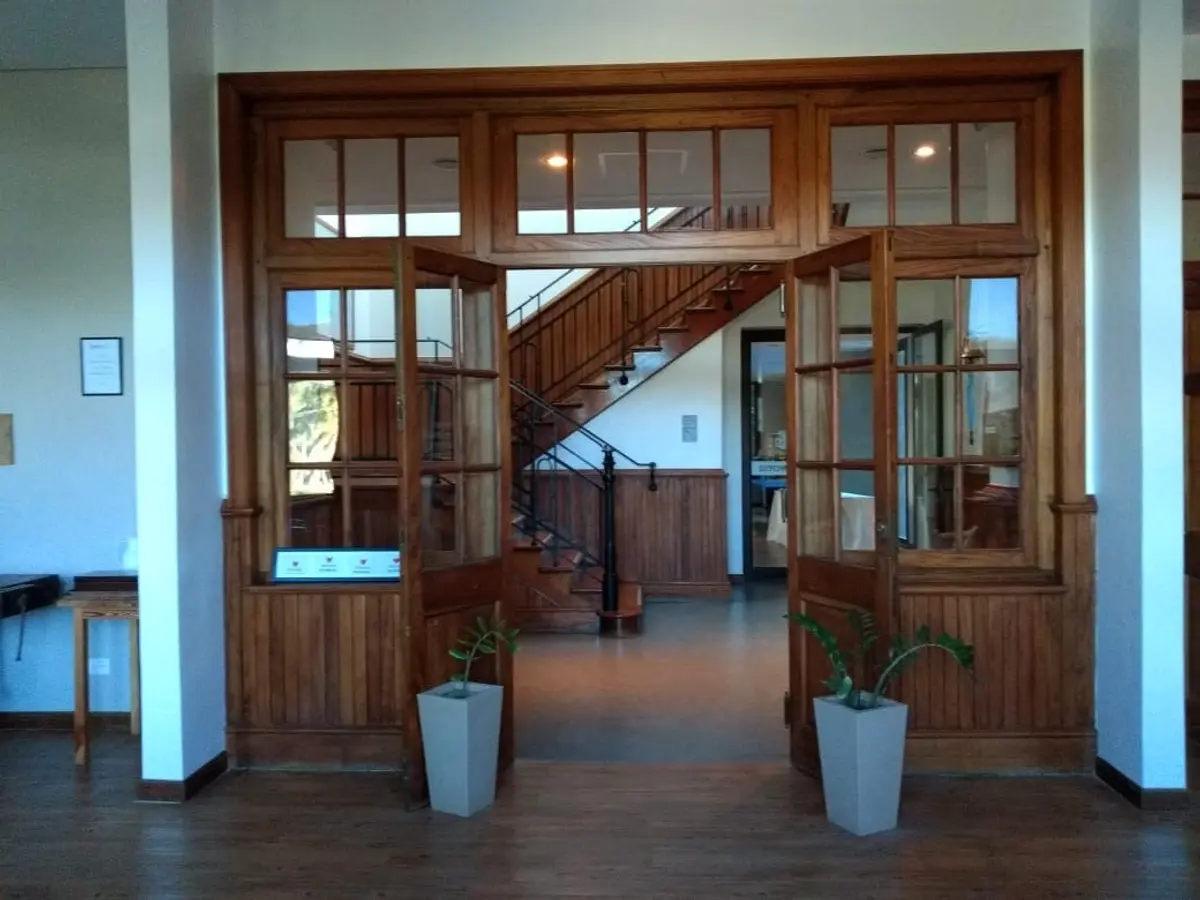 Hall de hotel con escalera de madera y detalles clásicos — proyecto St George´s College Quilmes Edificio Boarding House, por byb.arquitectas, en Quilmes