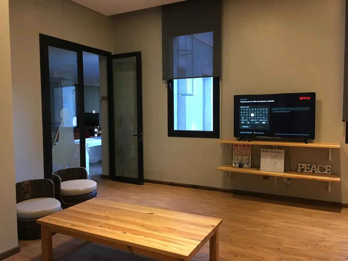 Sala de estar moderna com poltronas cinzas e mesa de madeira — projeto St George´s College Quilmes Edificio Boarding House, por byb.arquitectas, em Quilmes