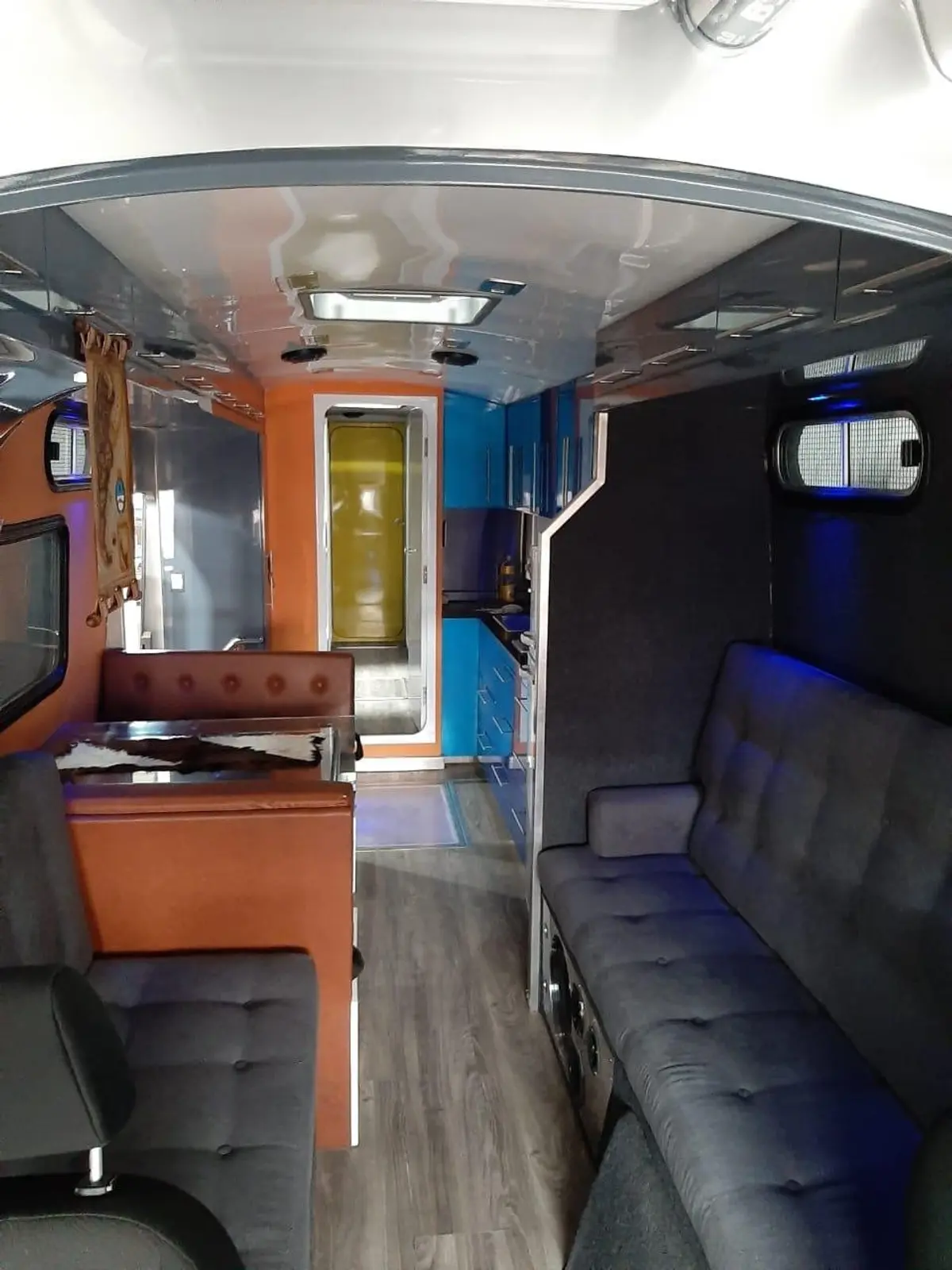 Interior de veículo com sofás cinzas e armários laranja e azul — projeto MOTOR - HOME, por Estudio Arq. Carolina Peruzzo, em Mar del Plata