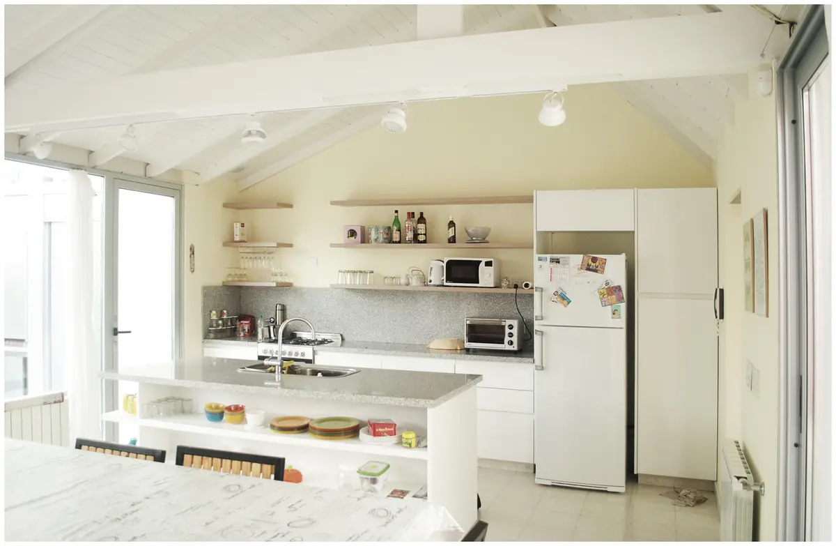 Cozinha moderna com tetos inclinados e vigas expostas — projeto casa mc, por GARAGE arquitectura, em Mar del Plata