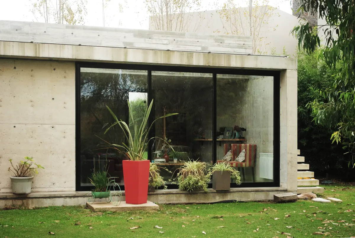 Fachada moderna brutalista com concreto aparente e grandes janelas — projeto casa s, por GARAGE arquitectura, em Rumencó