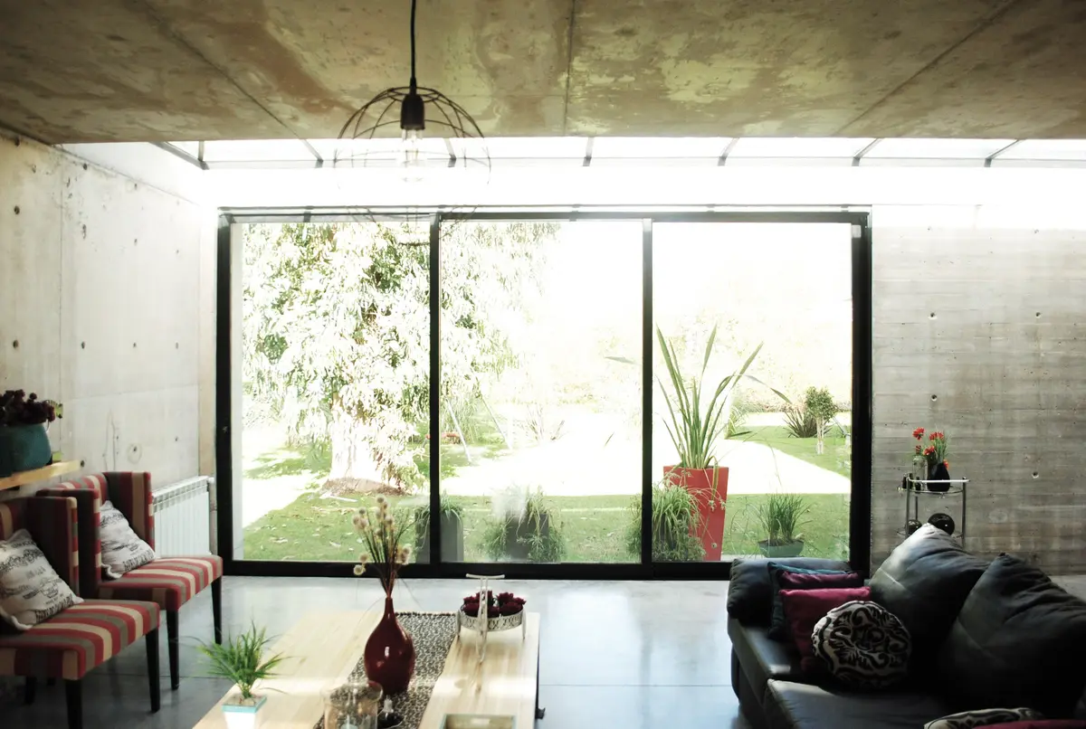 Sala de estar moderna com concreto aparente e amplas janelas — projeto casa s, por GARAGE arquitectura, em Rumencó