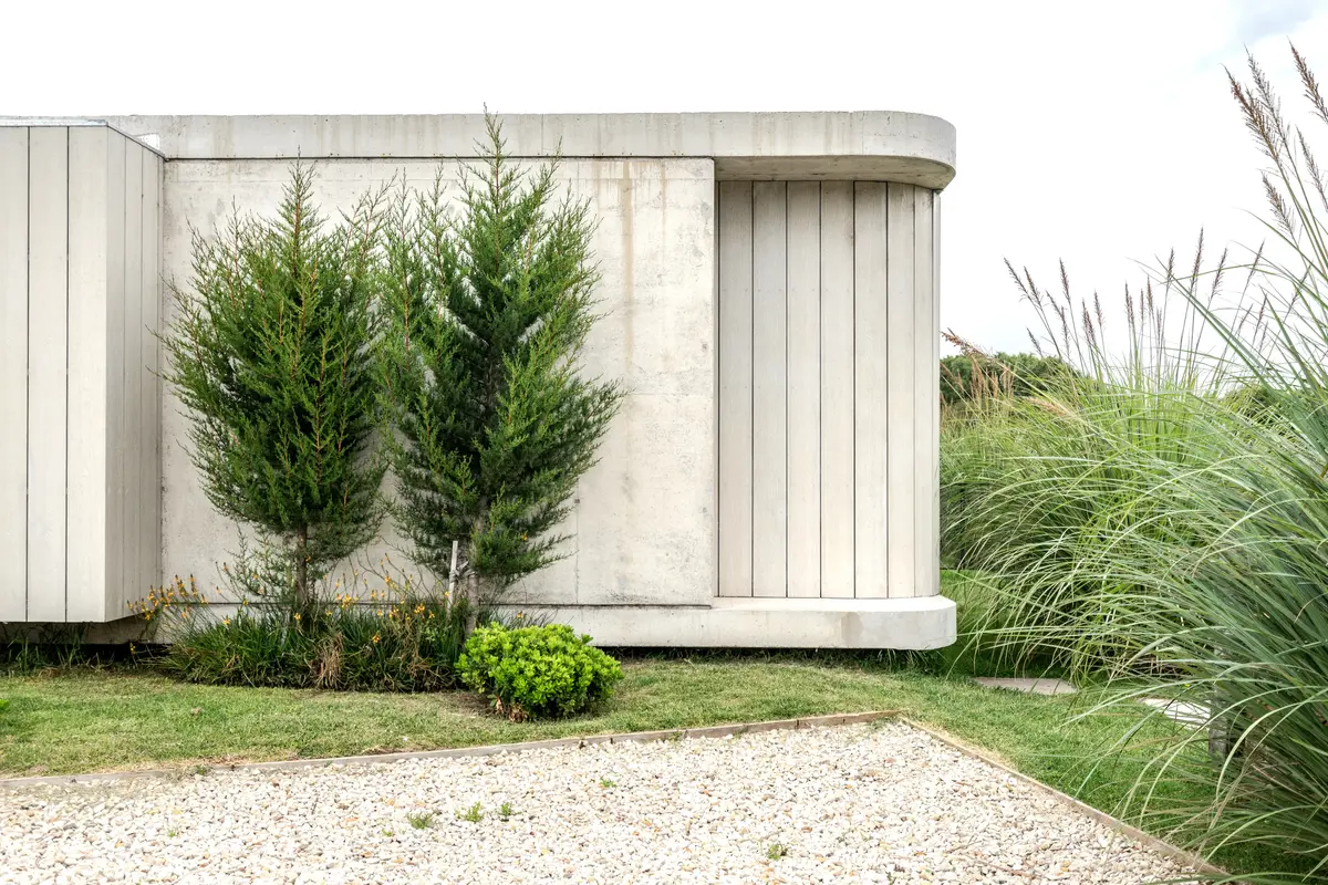 Fachada moderna com paredes curvas e paisagismo integrado — projeto casa sr, por GARAGE arquitectura