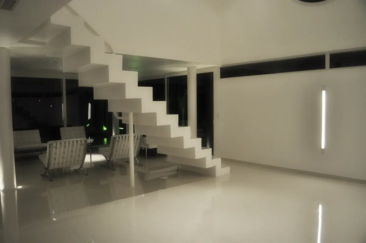 Escada flutuante minimalista com poltronas brancas e iluminação indireta — projeto CASA 120, por SCM ARQUITECTURA & CONSTRUCCIONES