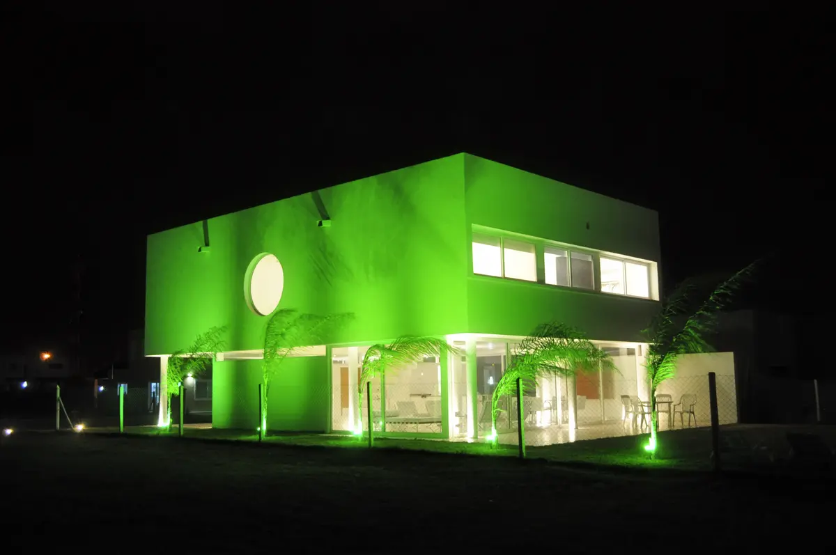 fachada moderna verde con iluminación nocturna y palmeras — proyecto CASA 120, por SCM ARQUITECTURA & CONSTRUCCIONES