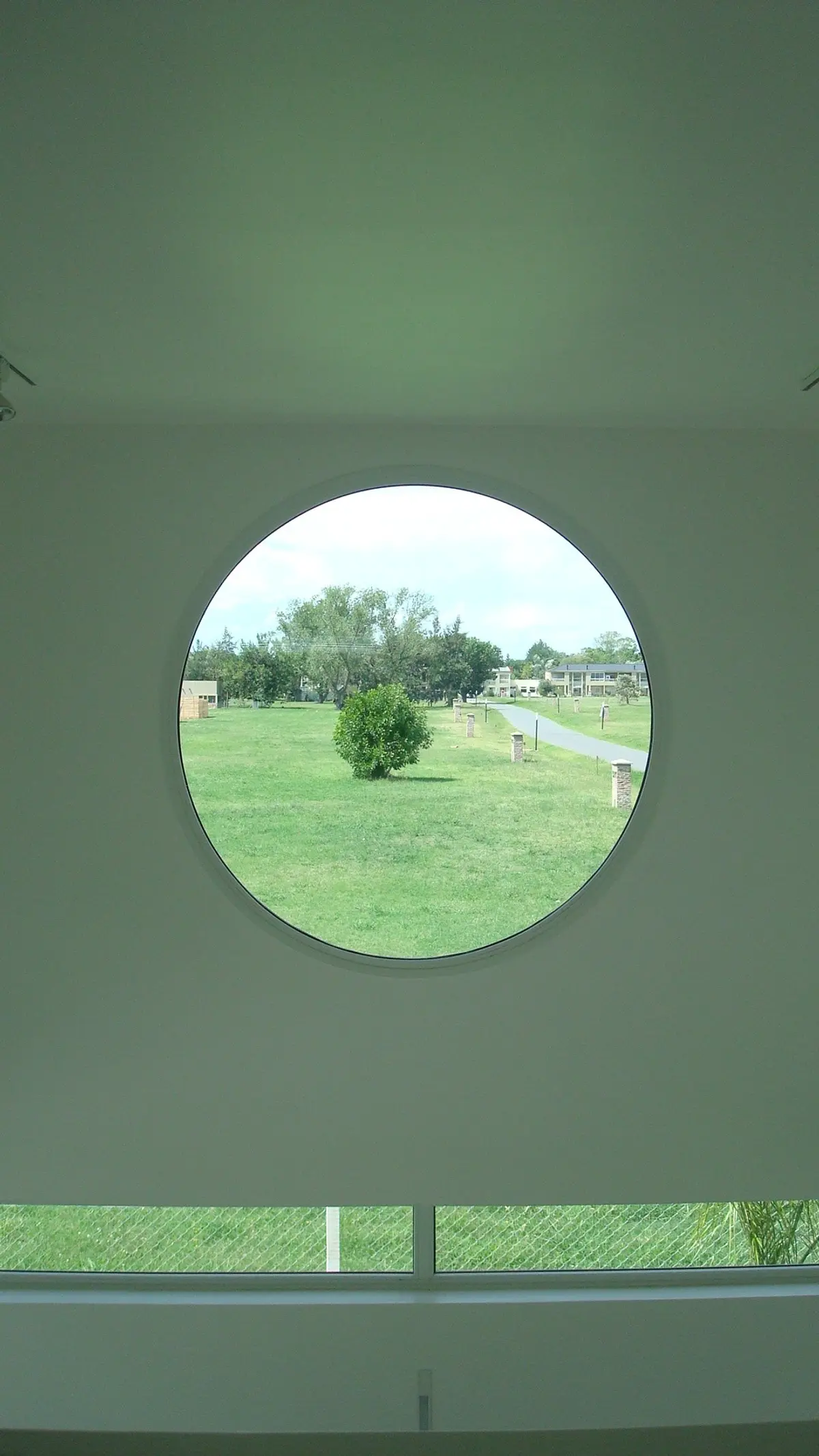 Janela redonda em fachada minimalista com vista para o campo — projeto CASA 120, por SCM ARQUITECTURA & CONSTRUCCIONES