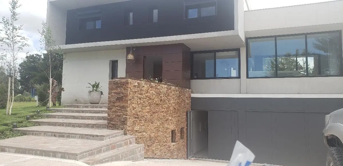 Casa moderna con fachada de piedra apilada y grandes ventanales — proyecto Casa Rumenco, por Estudio Arq. Carolina Peruzzo , en Rumencó