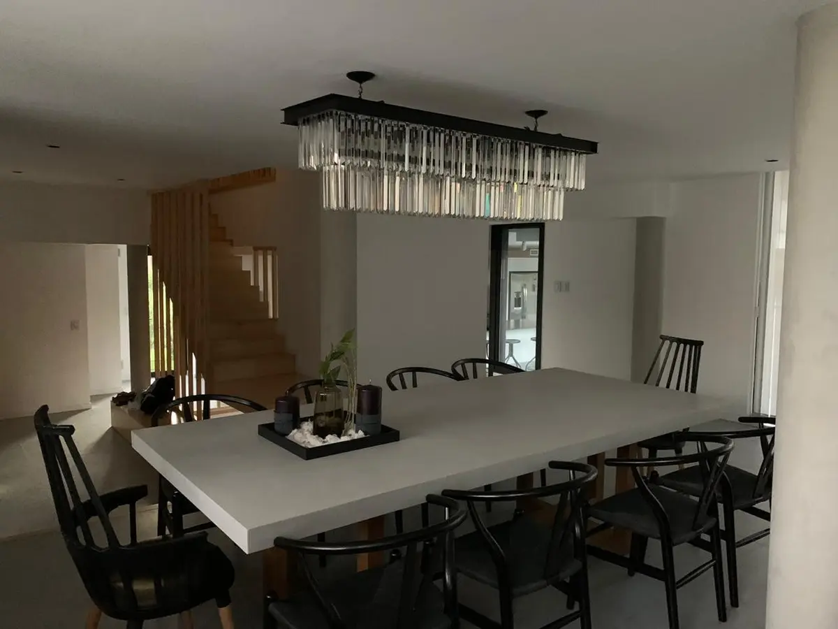 Sala de jantar moderna com mesa grande, cadeiras pretas e lustre de cristal — projeto Casa Rumenco, por Estudio Arq. Carolina Peruzzo, em Rumencó