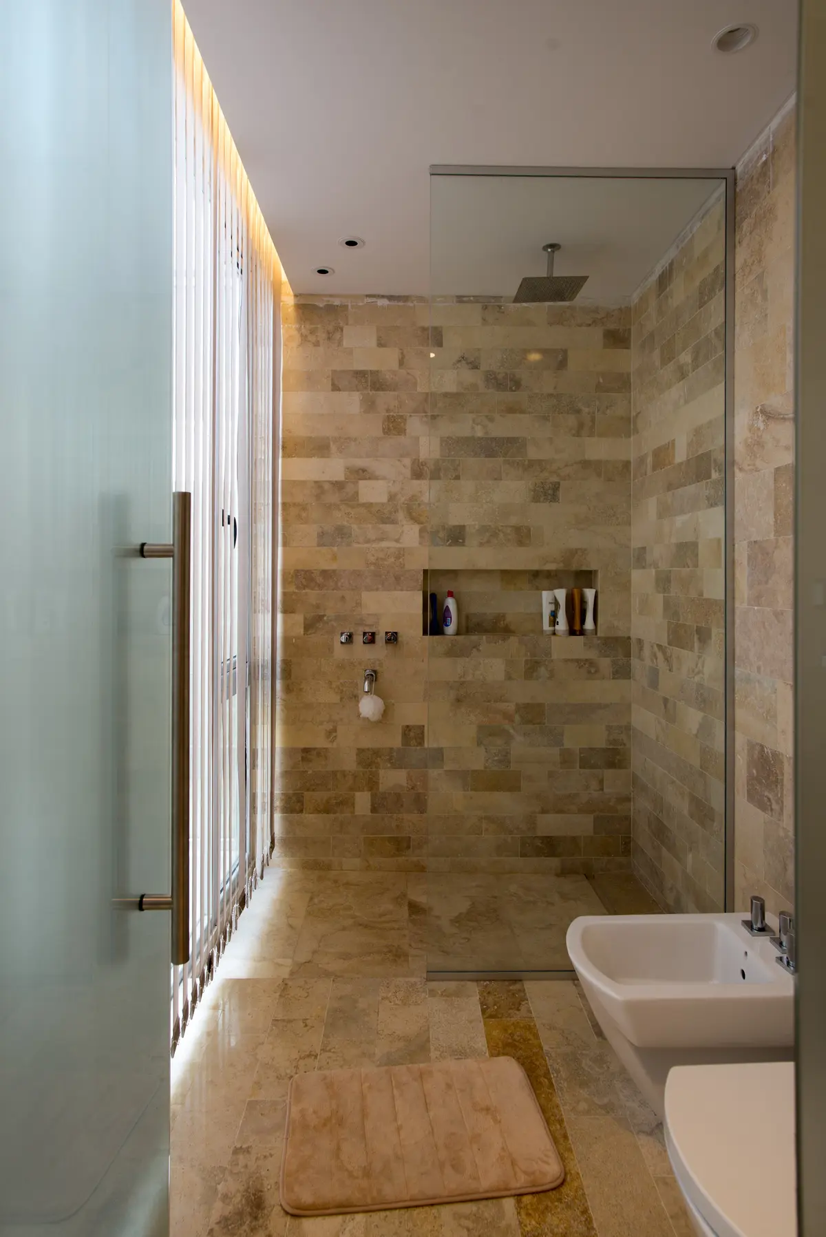 baño moderno con ducha amplia y revestimientos de piedra — proyecto Casa Berisso, por Mercedes  klappenbach, en Berisso