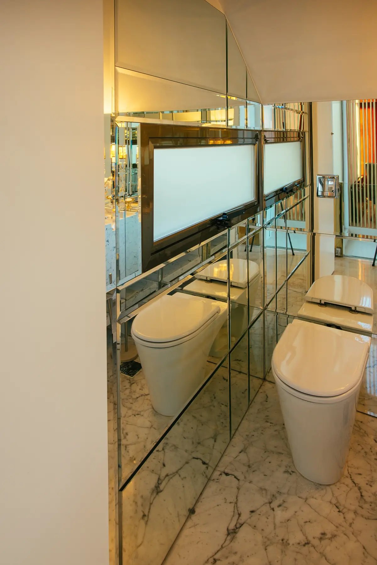 Baño moderno con paredes espejadas y dos inodoros — proyecto Grand Bell 60, por Mercedes  klappenbach, en City Bell