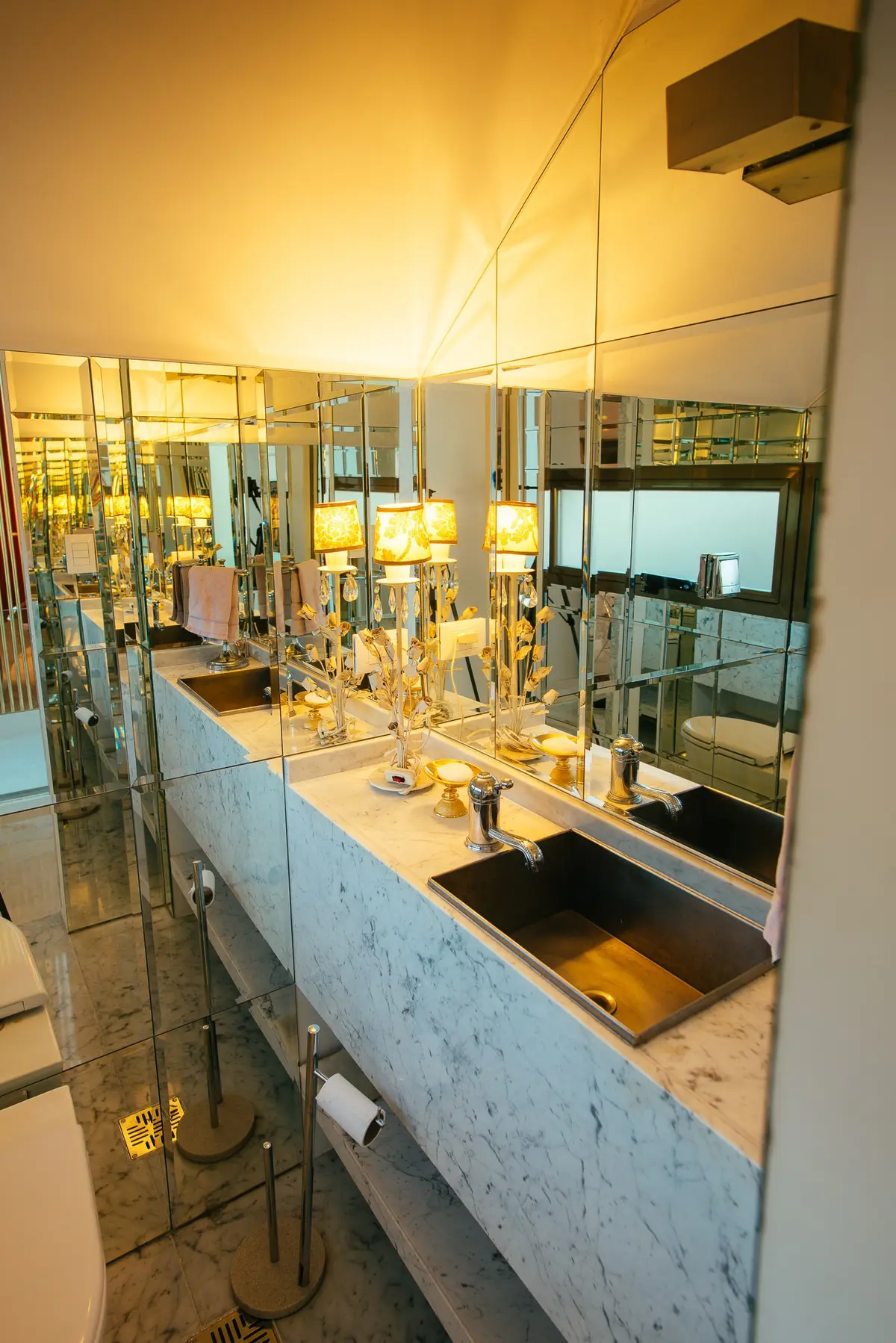 Baño lujoso con paredes espejadas y vanitory de mármol blanco — proyecto Grand Bell 60, por Mercedes  klappenbach, en City Bell
