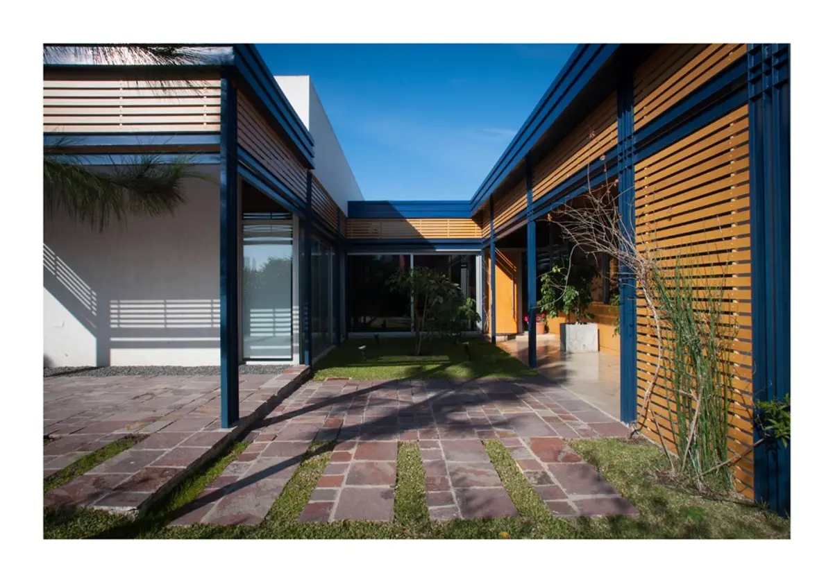 fachada moderna com pergolado de madeira e detalhes azuis — projeto Los Ceibos 60, por Mercedes  klappenbach, em La Plata