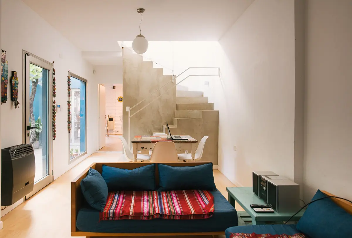 Living moderno con detalles boho y escalera flotante — proyecto Calle 67, por Mercedes  klappenbach, en La Plata