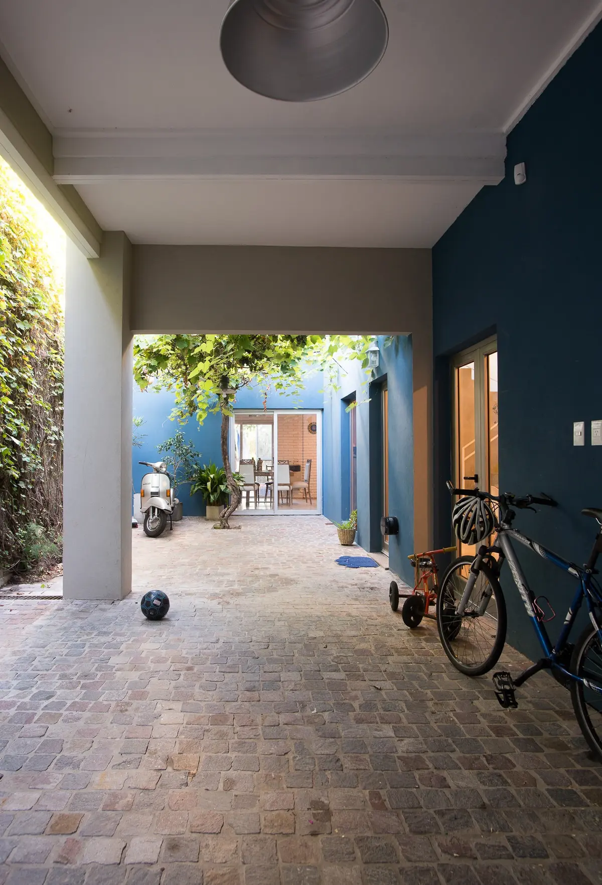 Patio azul moderno con scooter y bicicleta — proyecto Calle 67, por Mercedes  klappenbach, en La Plata