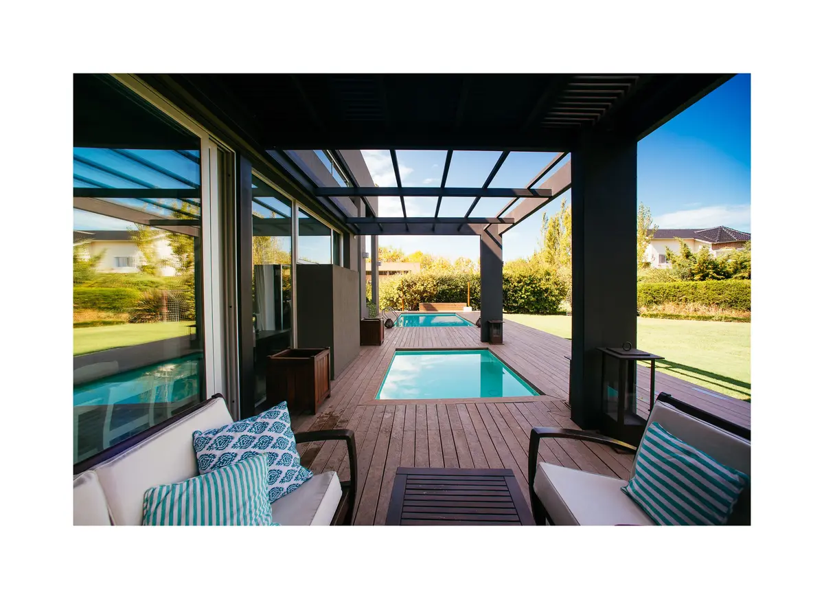 Área externa moderna com piscina, deck de madeira e pergolado — projeto Grand Bell 98, por Mercedes  klappenbach, em City Bell