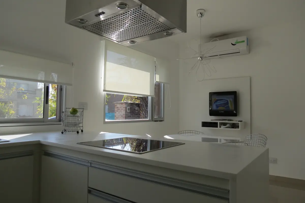 Cocina moderna minimalista con isla blanca y electrodomésticos integrados — proyecto Ampliación y refacción  San Agustín, por Olivieri Arquitectura, en Tigre