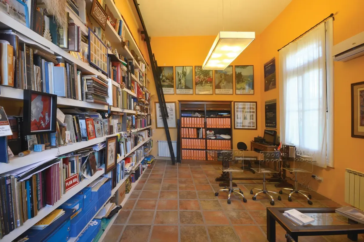 Oficina con estanterías altas de madera y pared naranja — proyecto Casa 14, por Estudio Martínez Nespral