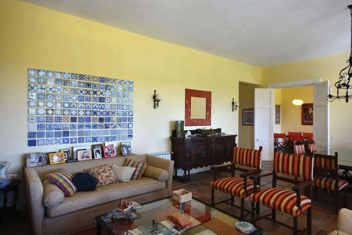 Sala de estar com sofá curvo, poltronas listradas e grande painel de azulejos — projeto Casa 14, por Estudio Martínez Nespral
