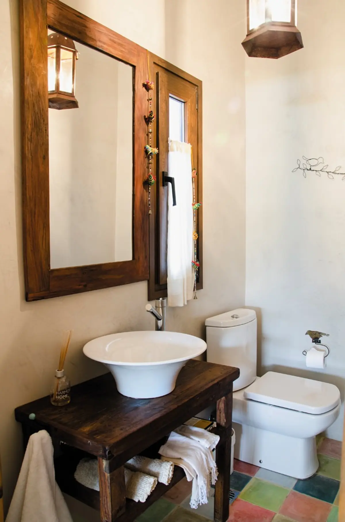 Baño rústico con lavabo de cerámica, espejo de madera y suelo de baldosas de colores — proyecto Casa 13, por Estudio Martínez Nespral