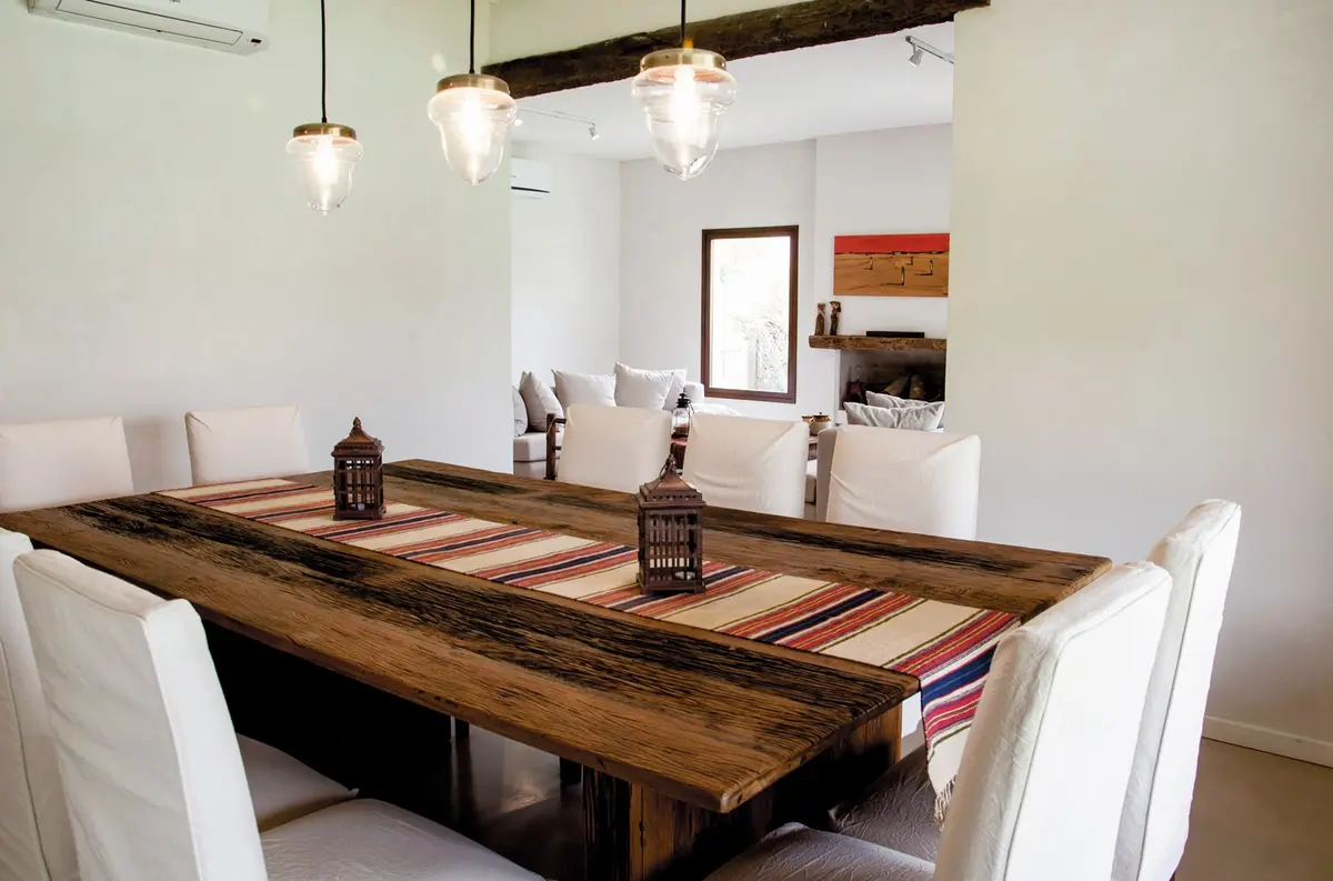 Sala de jantar rústica moderna com mesa de madeira e luminárias pendentes — projeto Casa 13, por Estudio Martínez Nespral