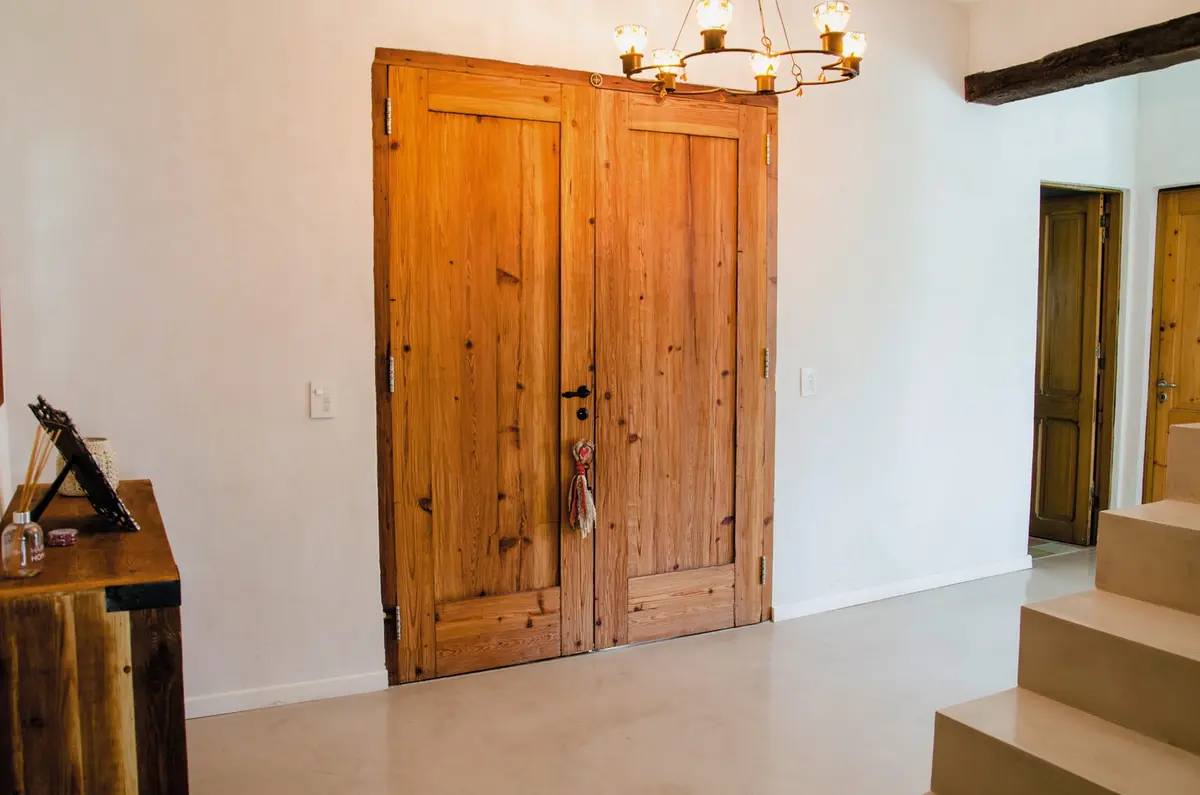 Puerta doble de madera rústica y candelabro antiguo — proyecto Casa 13, por Estudio Martínez Nespral